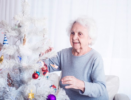 elderly lady decorating christmas tree in care home